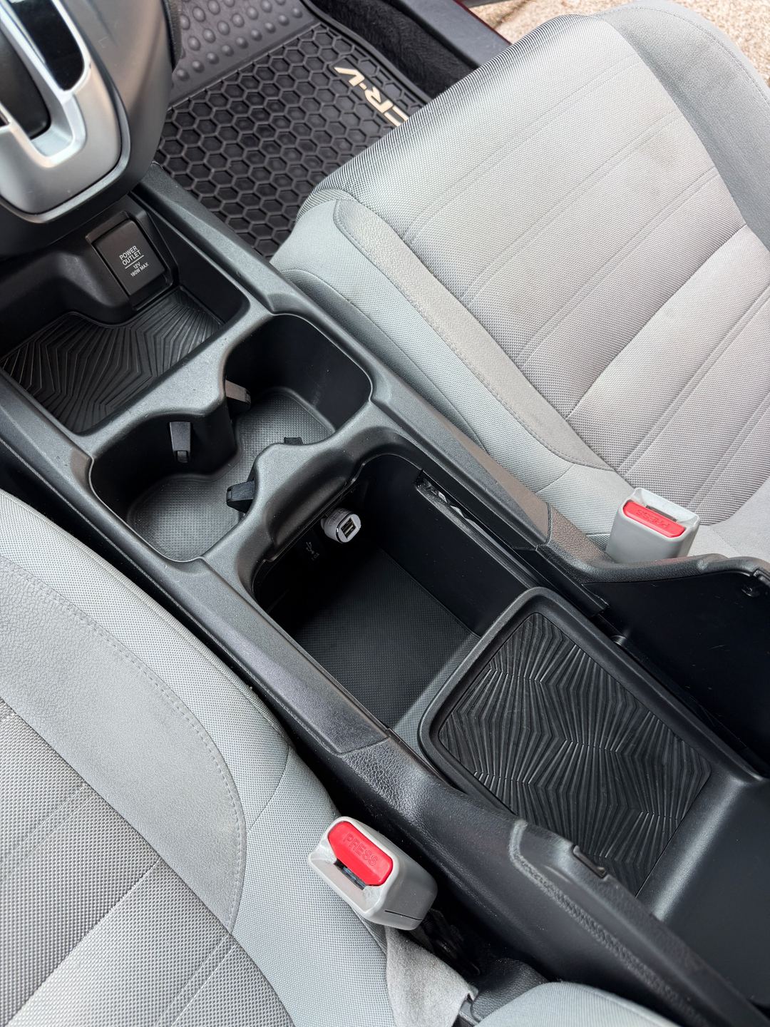 Centre console of a maroon Honda CR-V after detailing, the storage bin and cupholders empty and clean