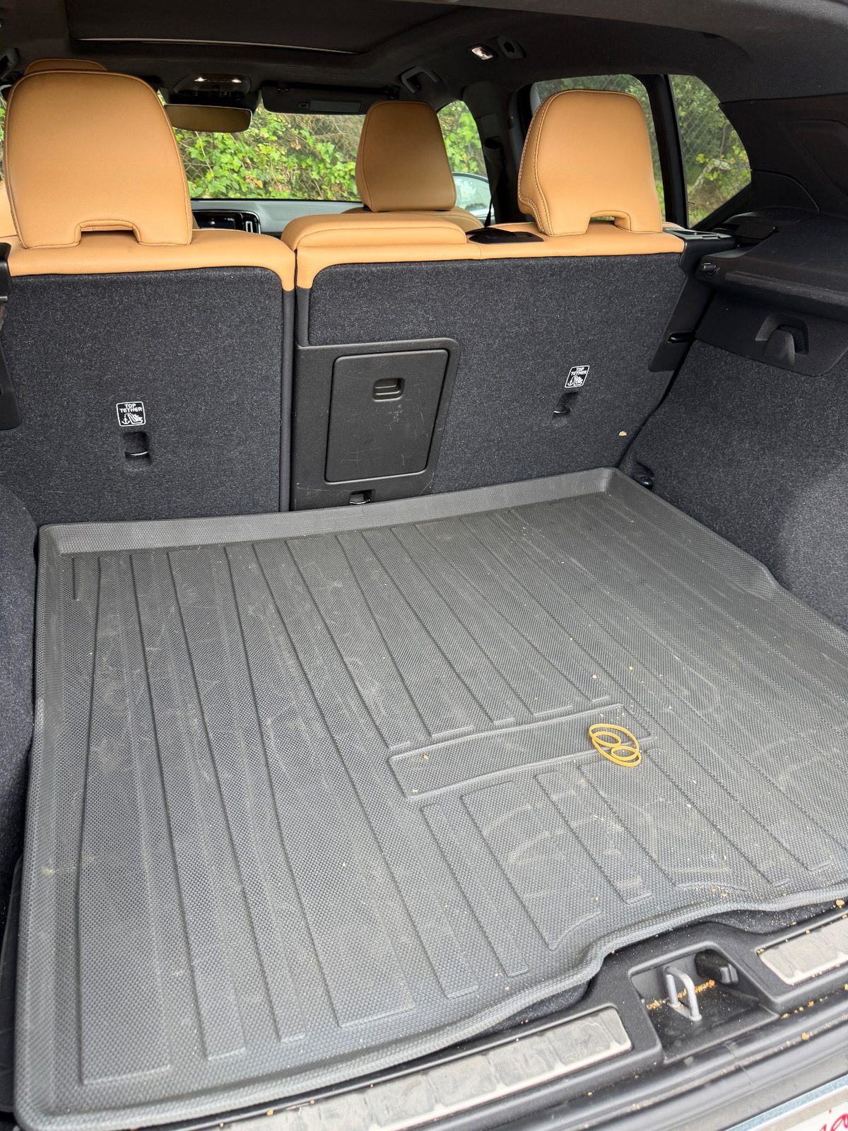 Cargo area of a Volvo XC40 before detailing, with grit and a rubber band on the liner