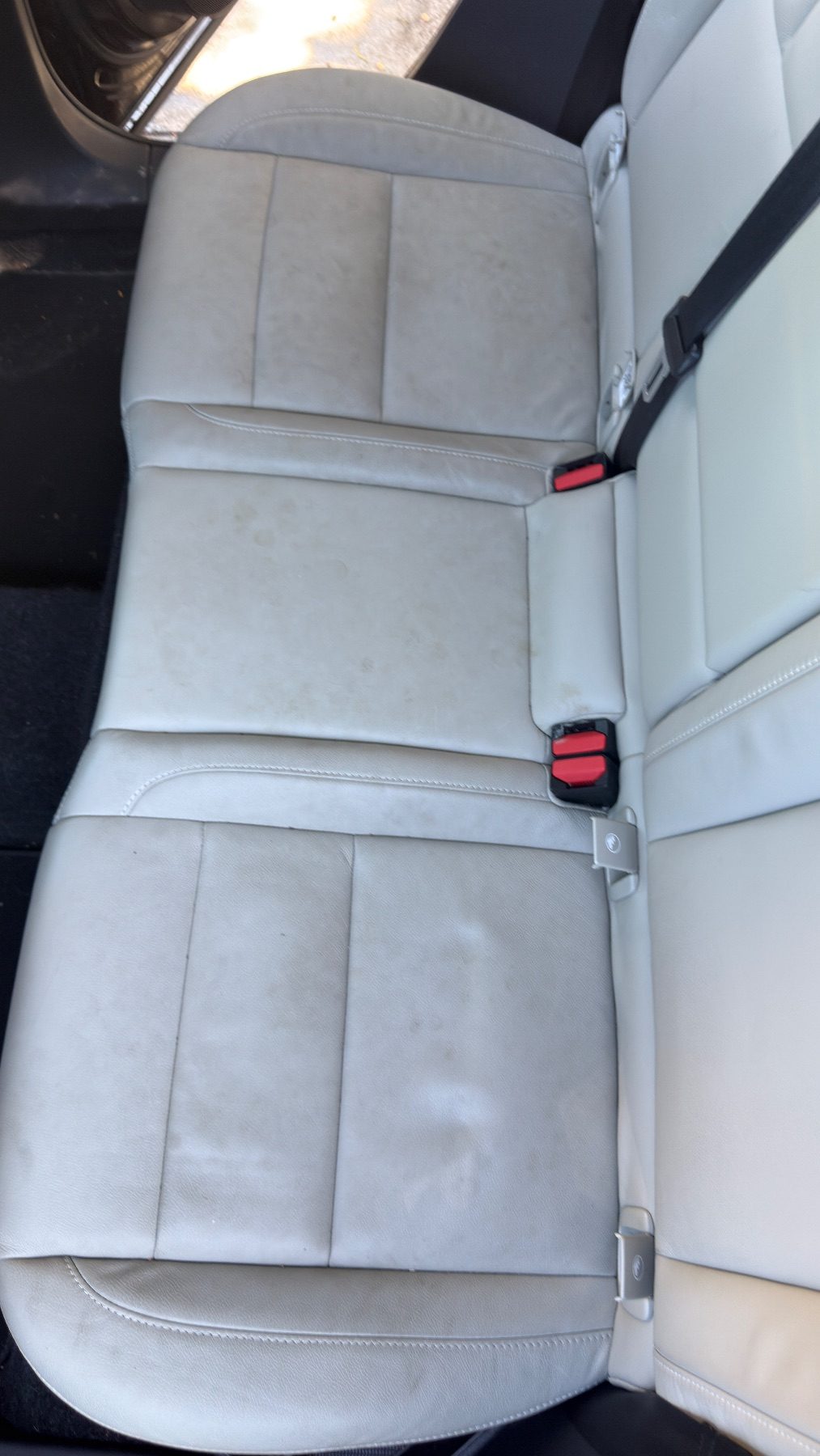 Top-down view of a Volvo XC40 rear bench with brown spotting and soiling on the leather before detailing