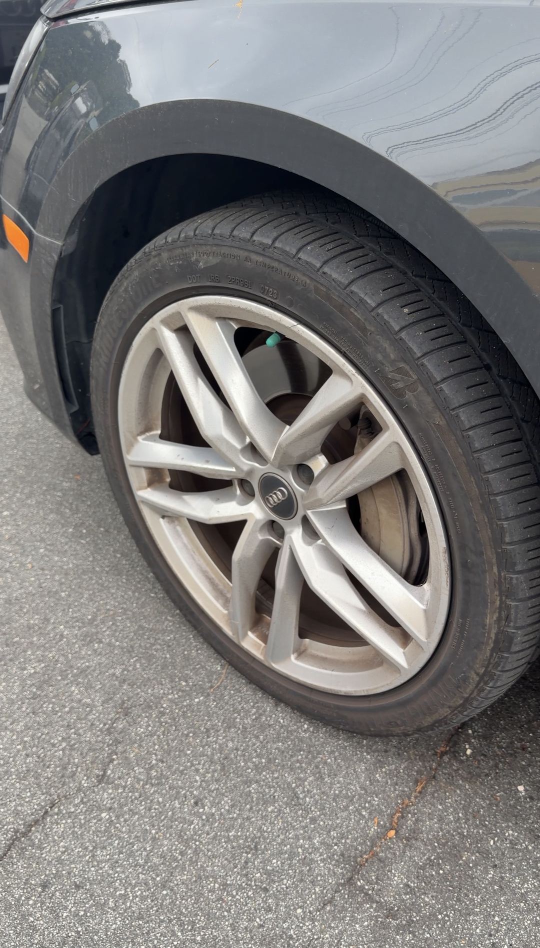 Brake dust on the driver-side front twin five-spoke alloy wheel of a grey Audi A4