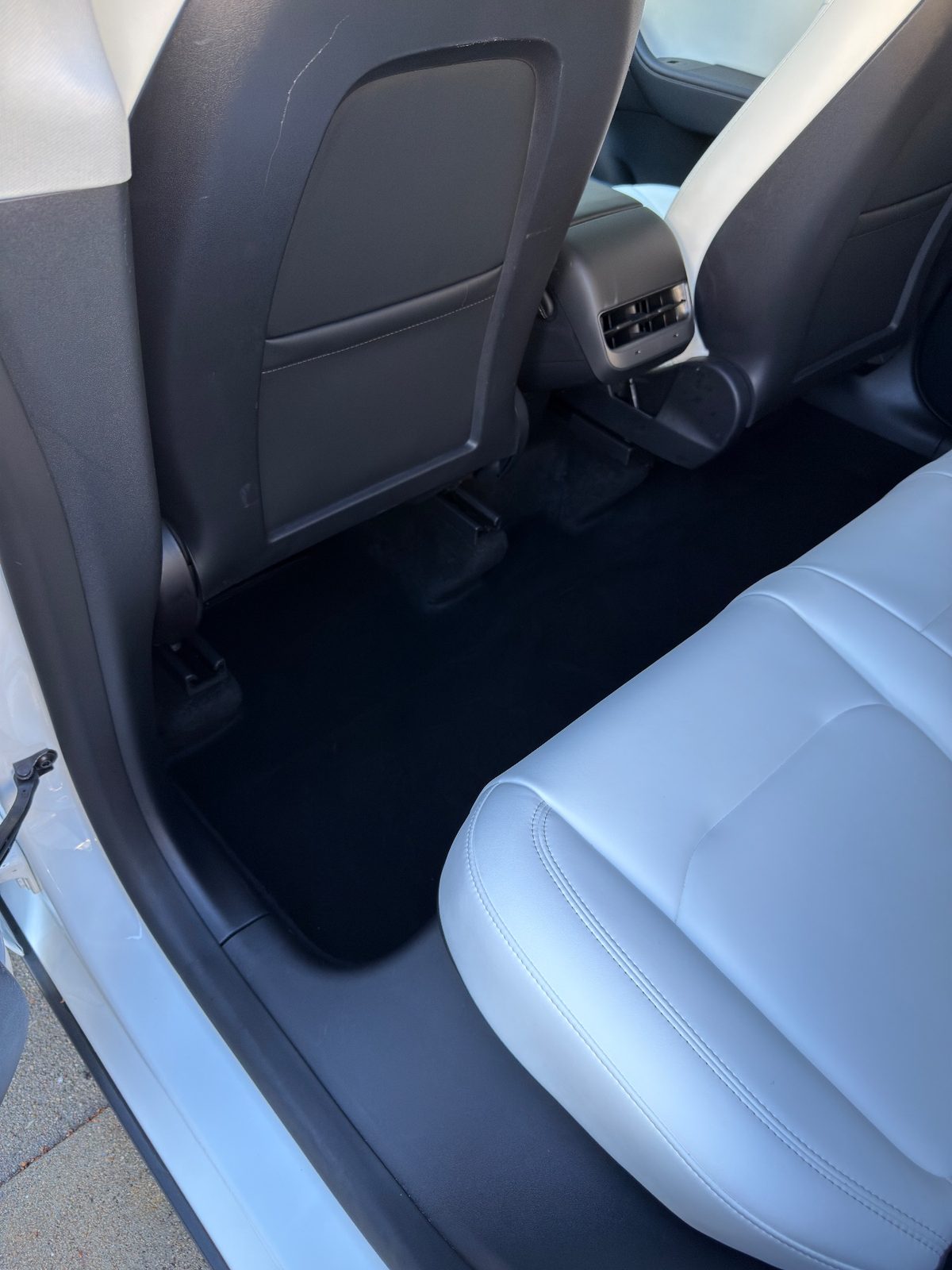 Clean rear driver-side footwell and seatback panel of a Tesla Model Y after detailing