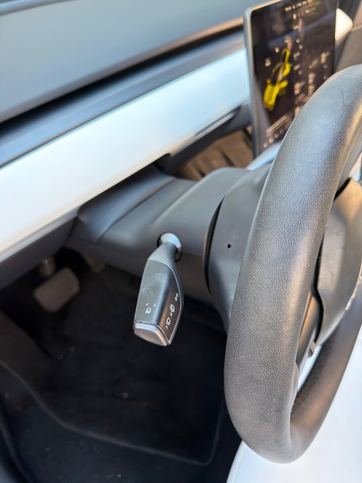 Steering column and driver carpet of a white Tesla Model Y before detailing