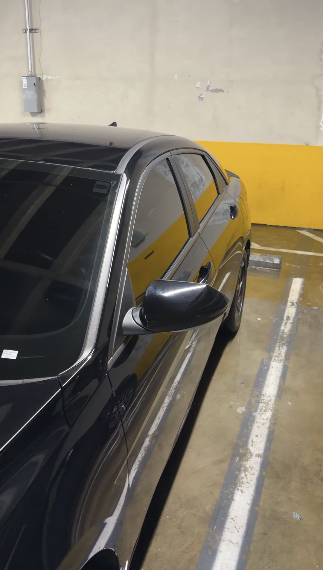 Glossy driver side of a washed black Hyundai Elantra in a parking garage