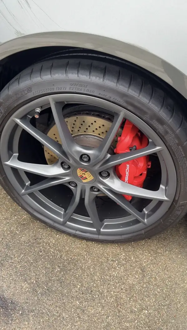 Clean Porsche wheel with a dressed tyre and red brake caliper after a mobile detail.