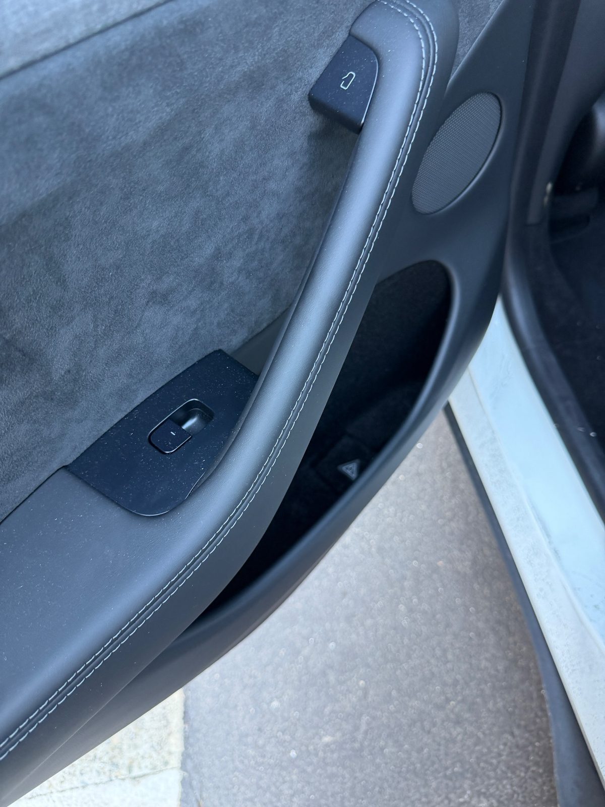 Rear door panel of a white Tesla Model Y before cleaning, light dust on the suede insert