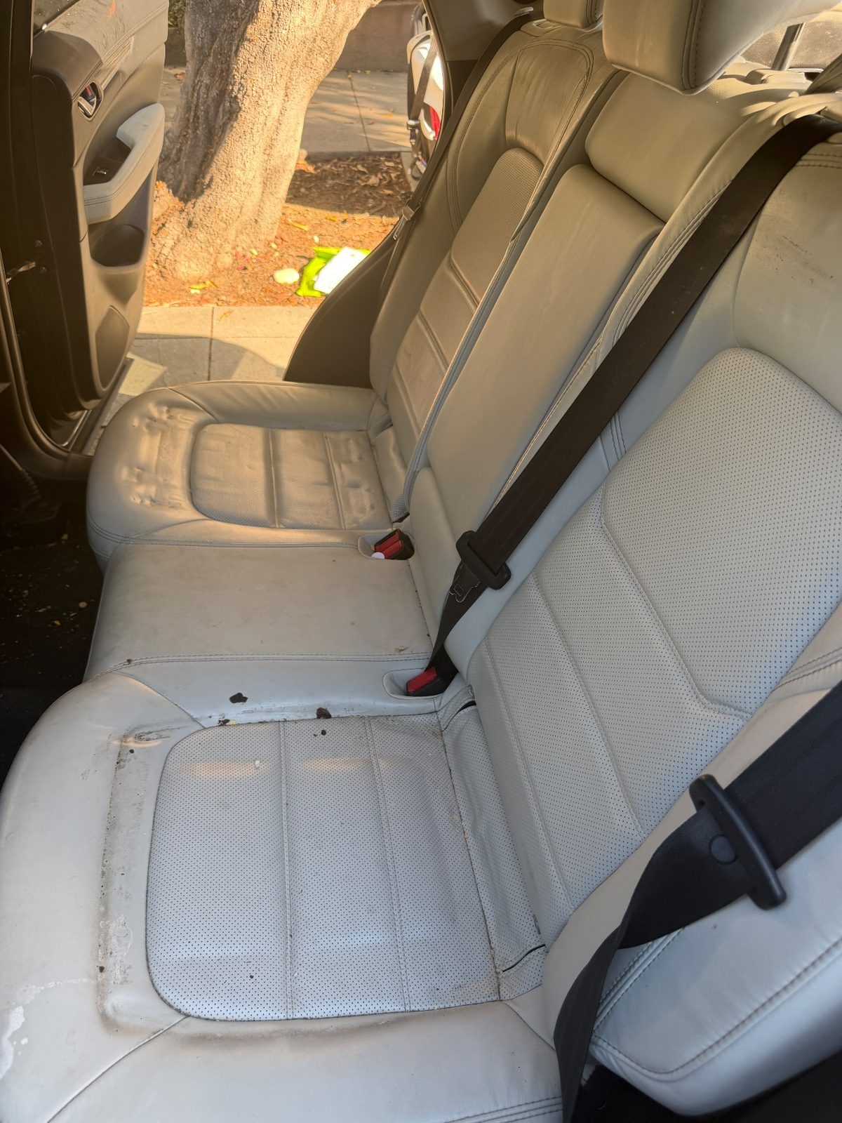 Rear seat of a dark blue Mazda CX-5 before cleaning, leather cushions spotted and soiled