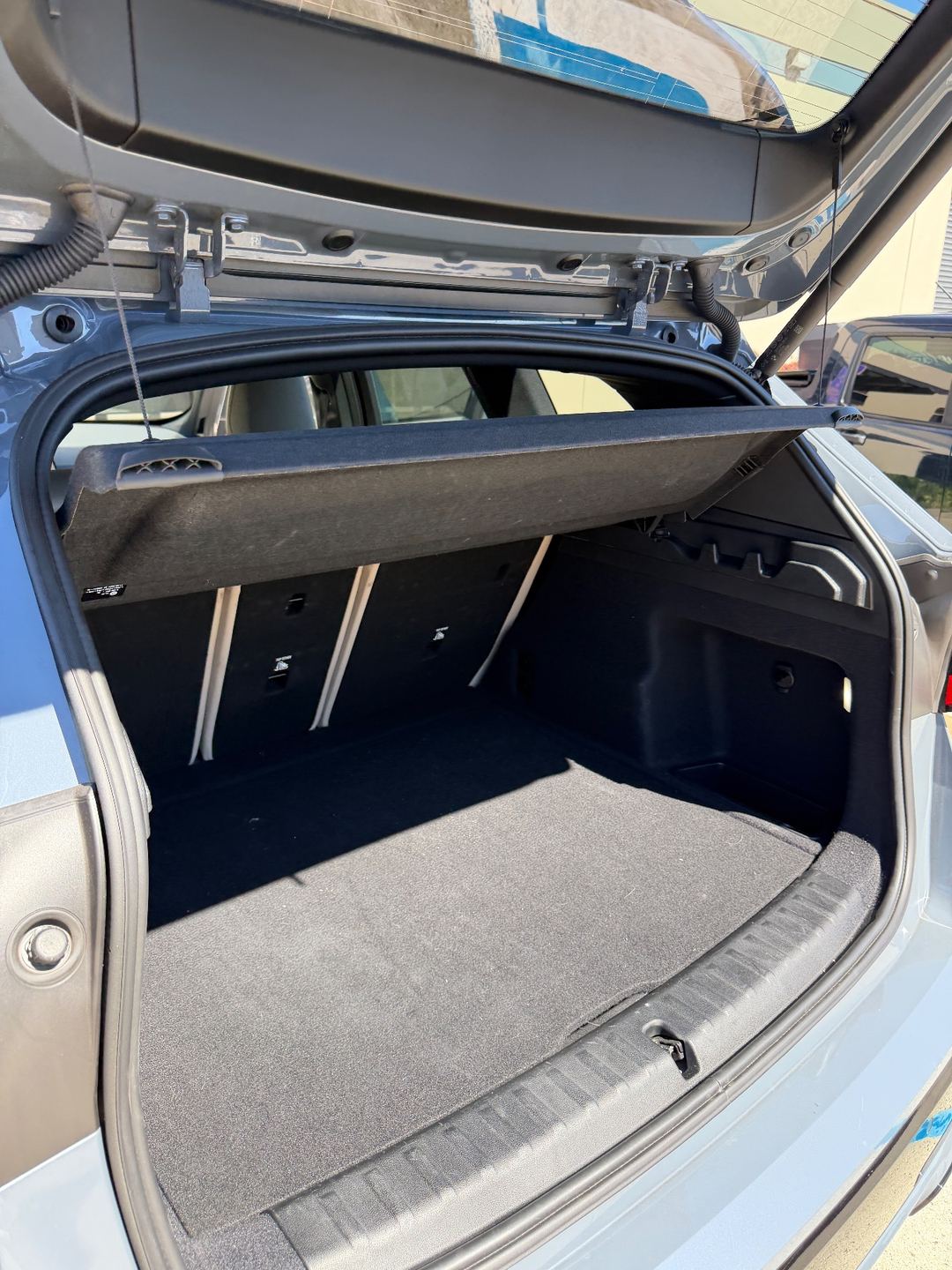 Cargo area of a grey BMW X1 before detailing, with lint on the carpet