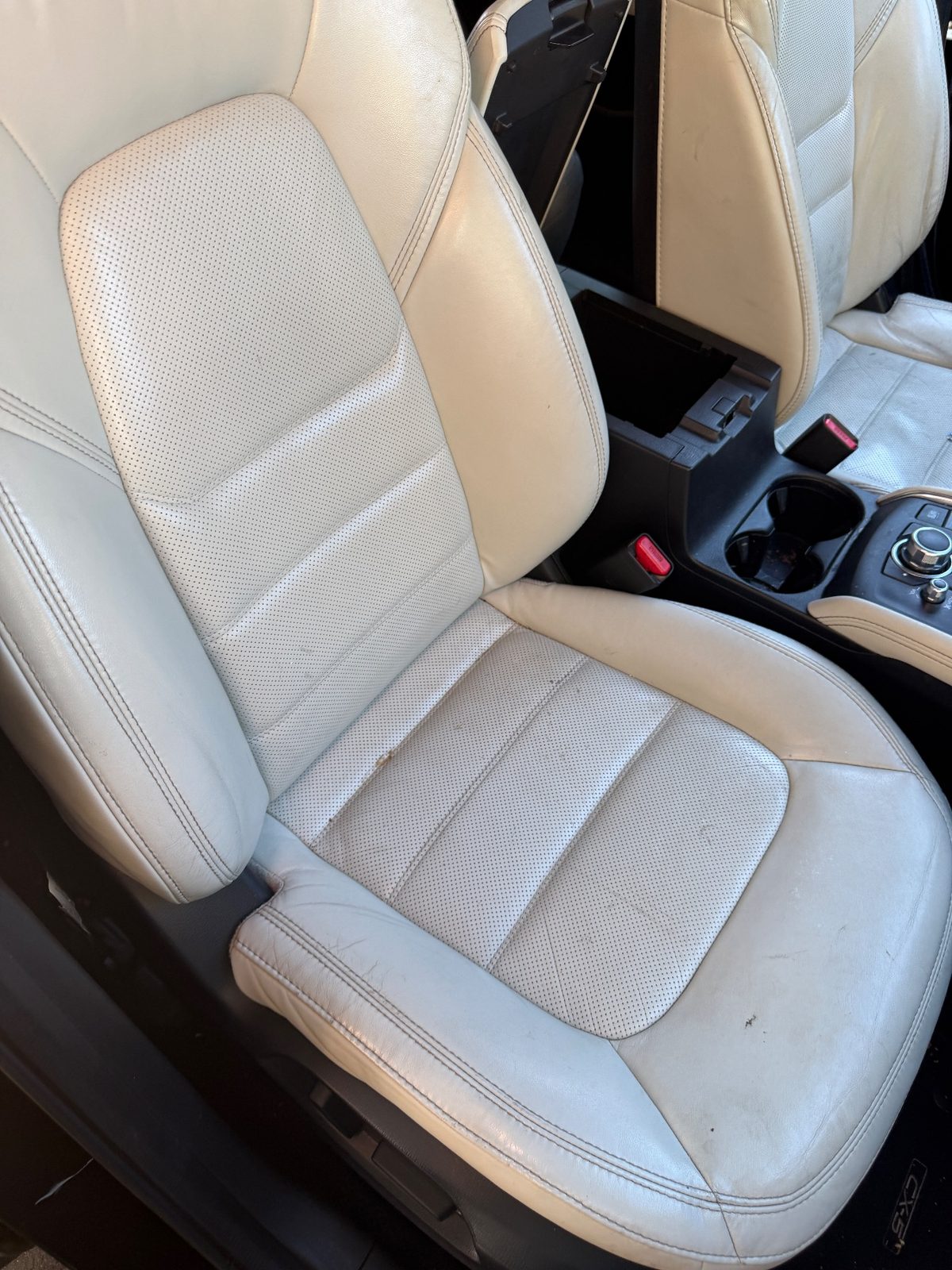 Front passenger seat of a dark blue Mazda CX-5 before cleaning, leather with dark specks and grime