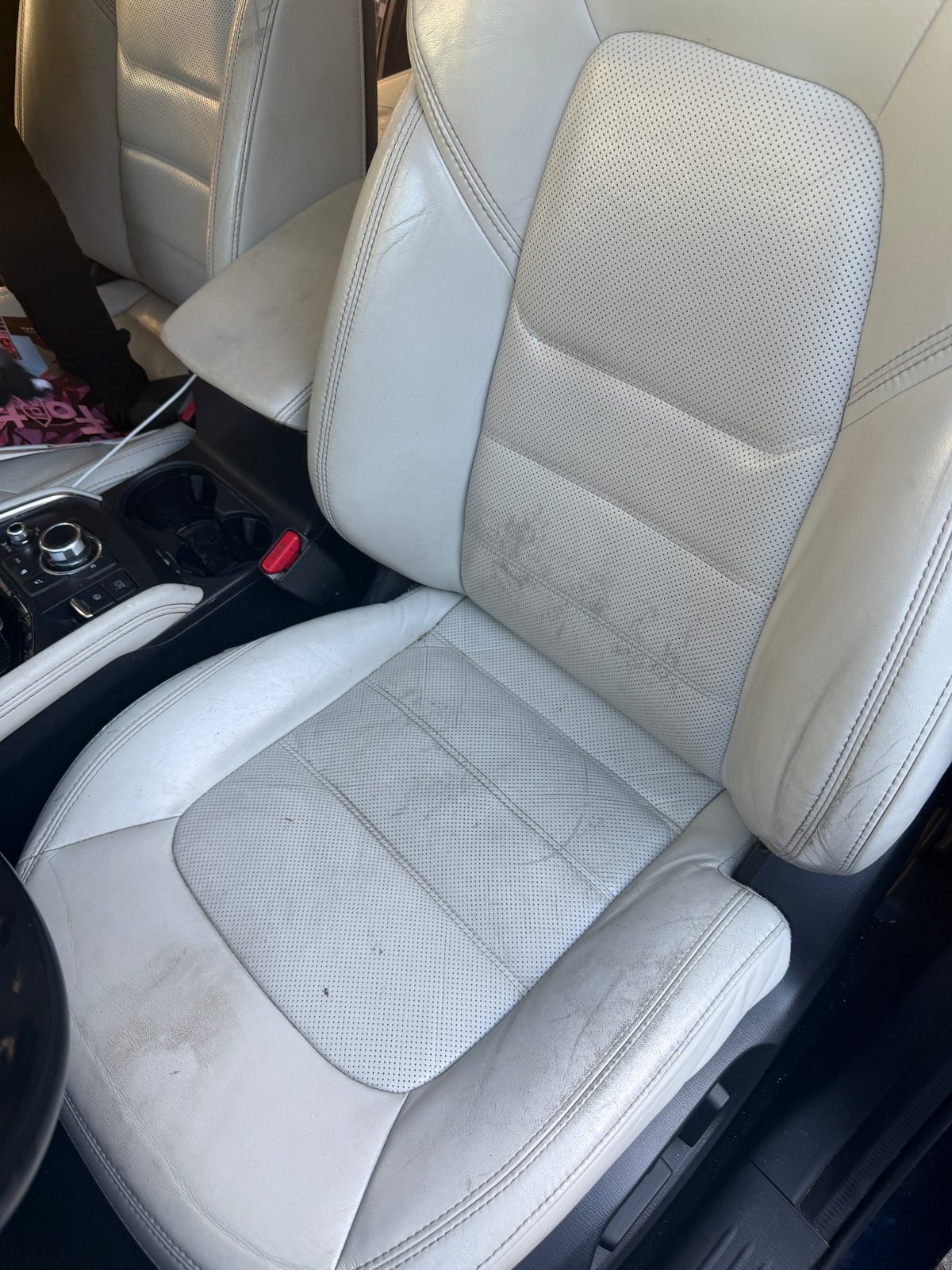 Driver seat of a dark blue Mazda CX-5 before cleaning, leather marked with dark soil and grime