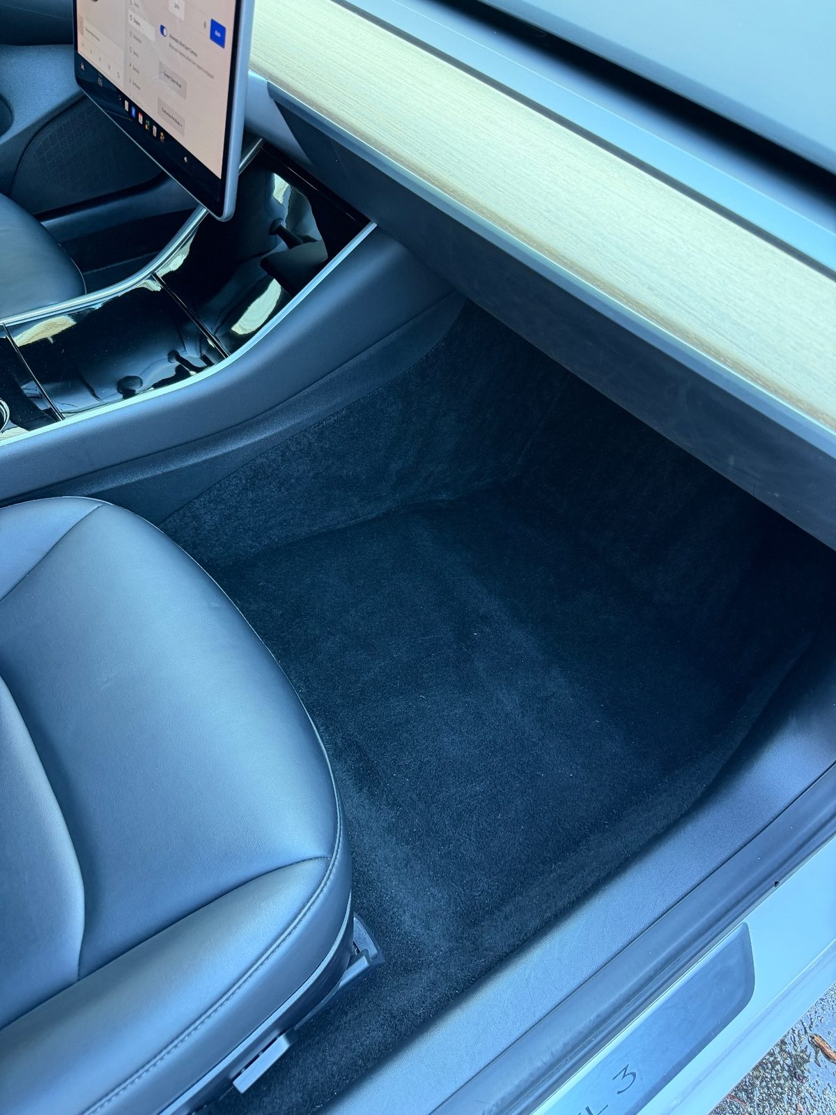 Passenger footwell of a white Tesla Model 3 after detailing, clean carpet