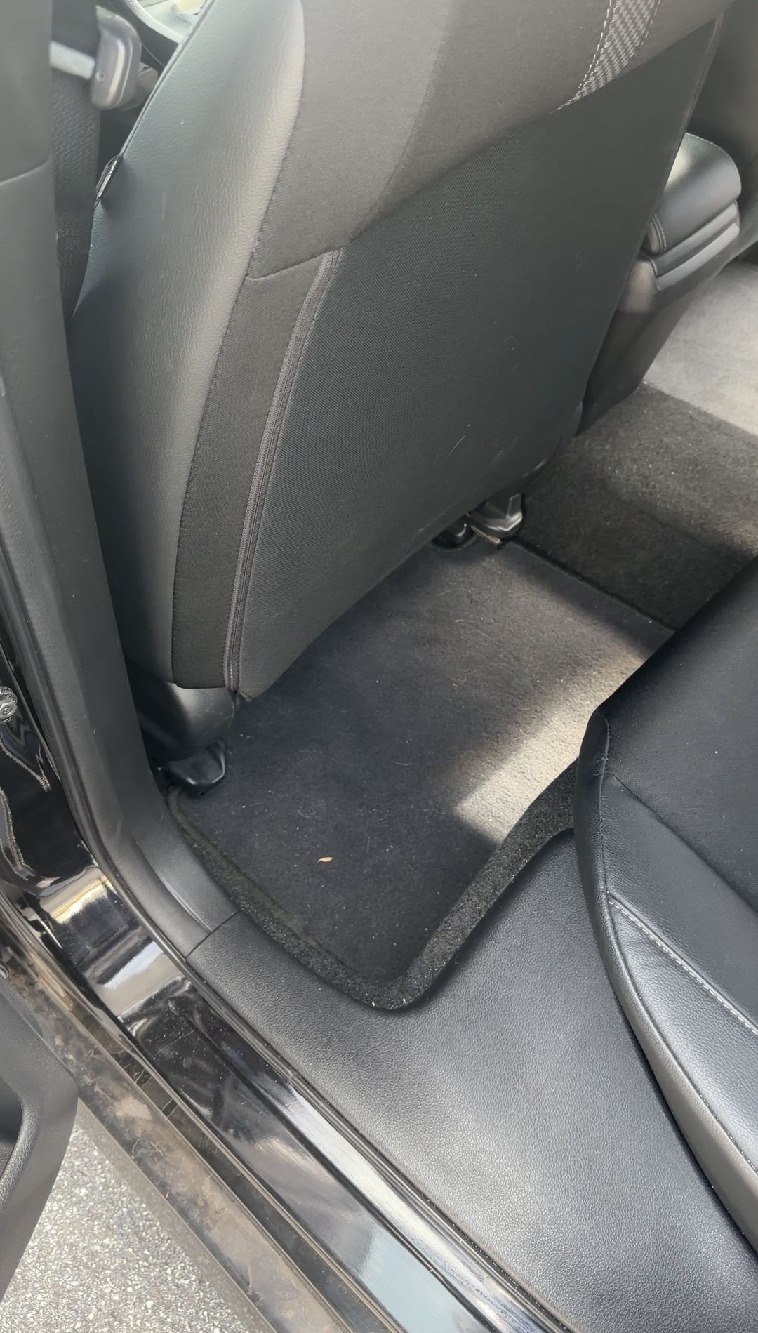 Dirty rear floor mat in a Honda Civic before vacuuming