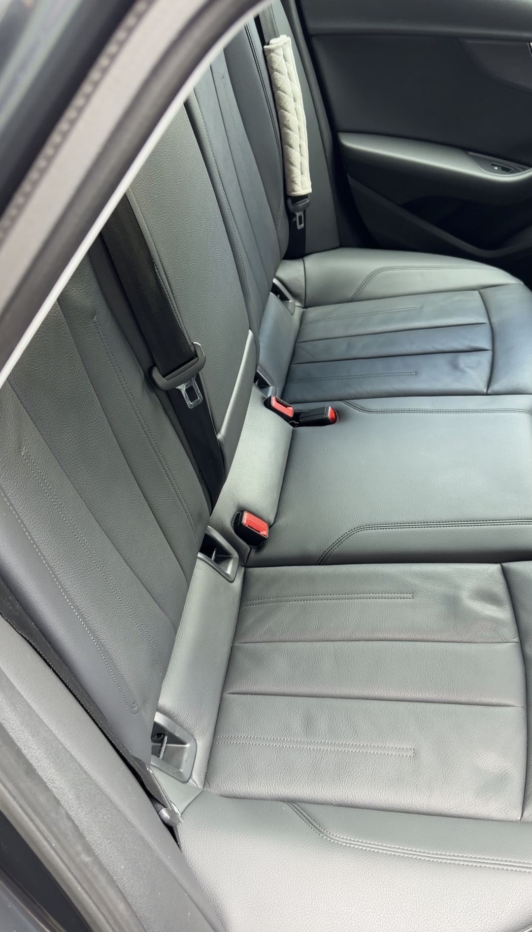 Clean black leather rear bench of an Audi A4 seen from the passenger-side rear door