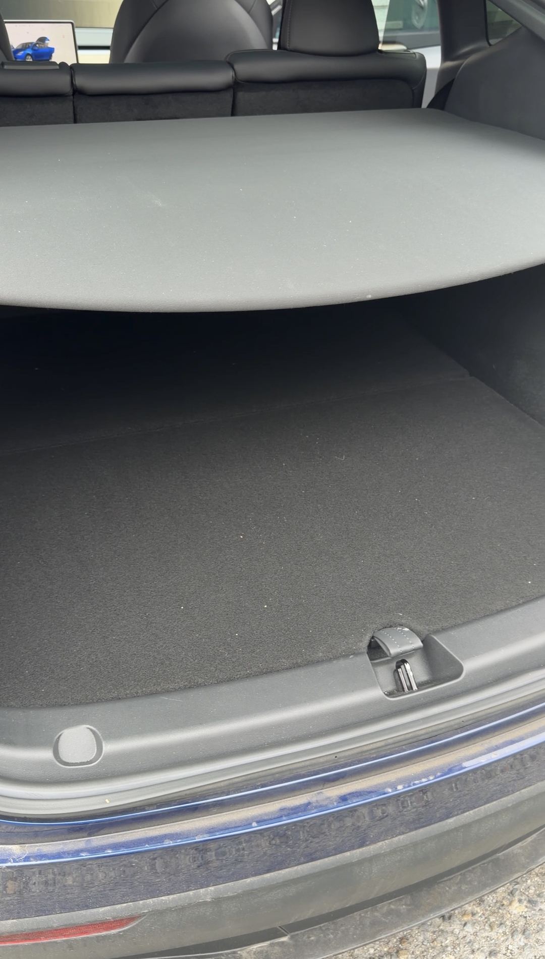 Rear cargo area of a Tesla Model Y with the parcel shelf fitted, before cleaning.