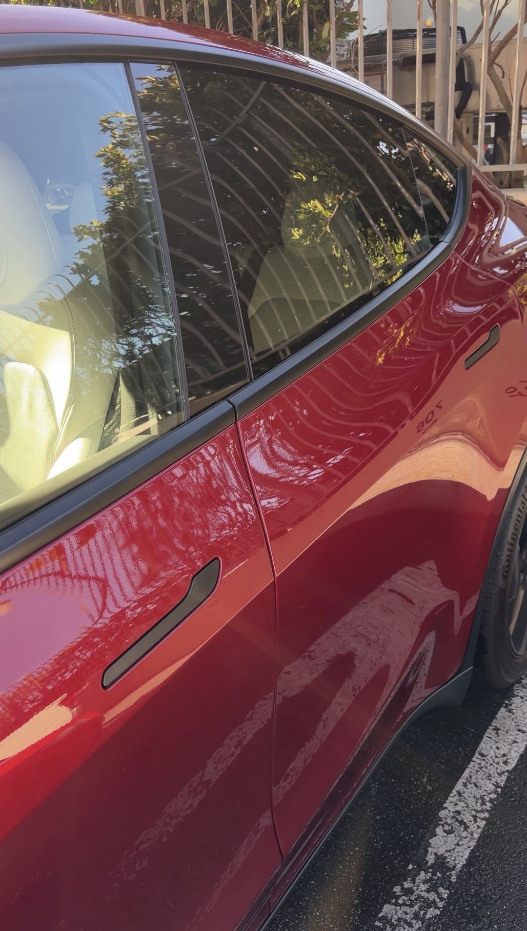 Mirror-clean side glass and paintwork of a red Tesla Model Y after detailing