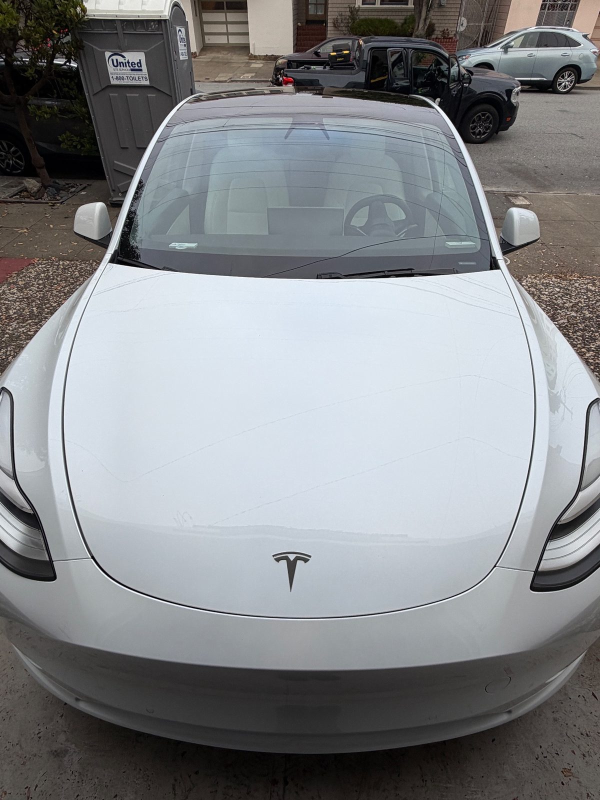 Front of a white Tesla Model Y after detailing, with a clean hood and windshield