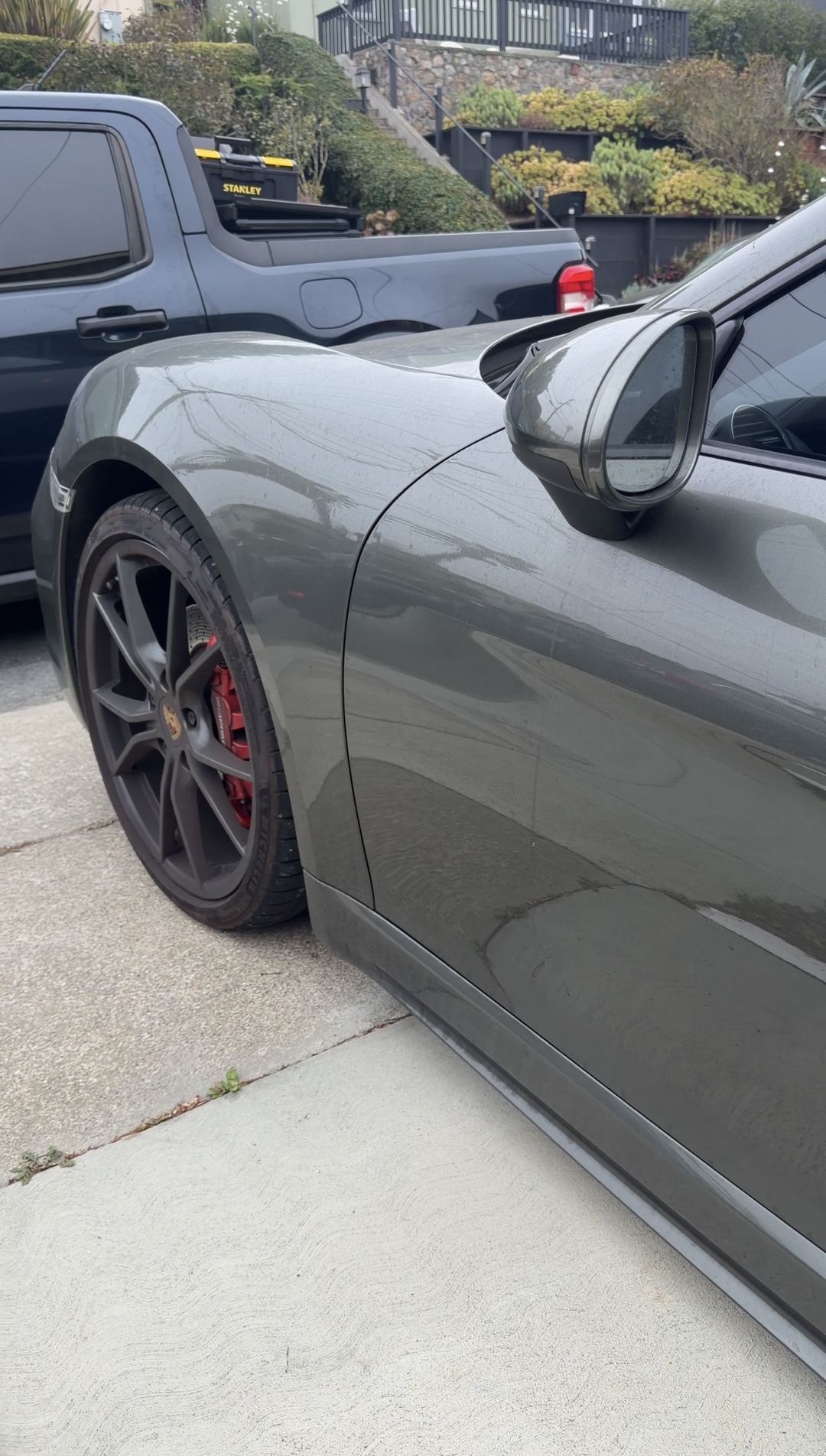 Driver's-side front fender and mirror of a green Porsche 718 Cayman S before cleaning.