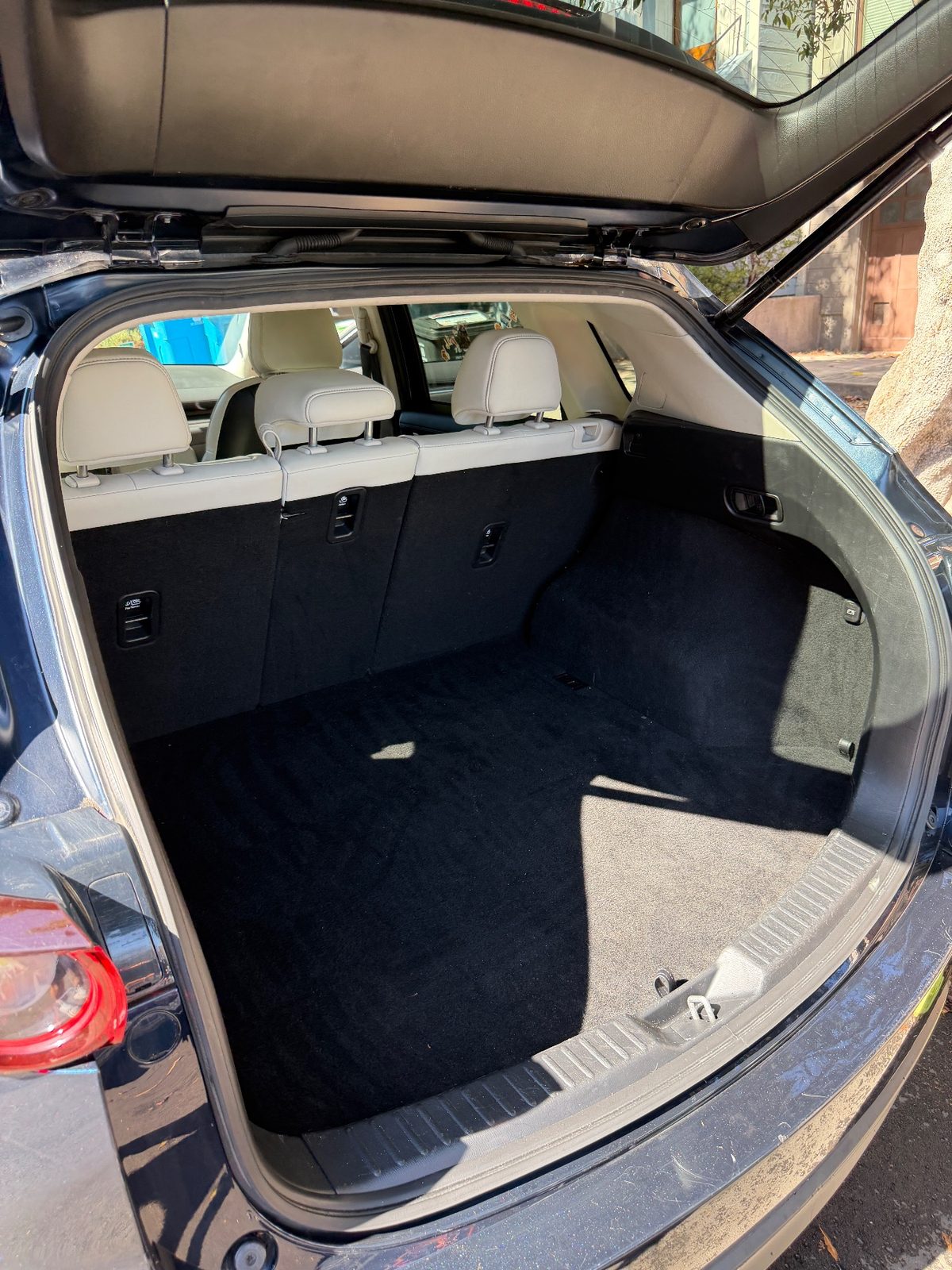 Clean cargo area of a dark blue Mazda CX-5 after detailing, freshly vacuumed black carpet
