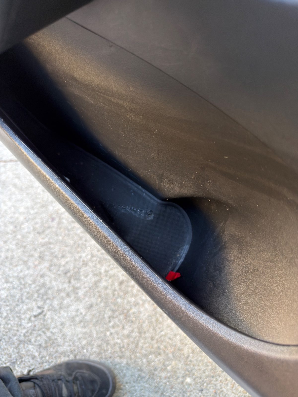 Dusty door pocket and lower door card inside a white Tesla Model Y before cleaning