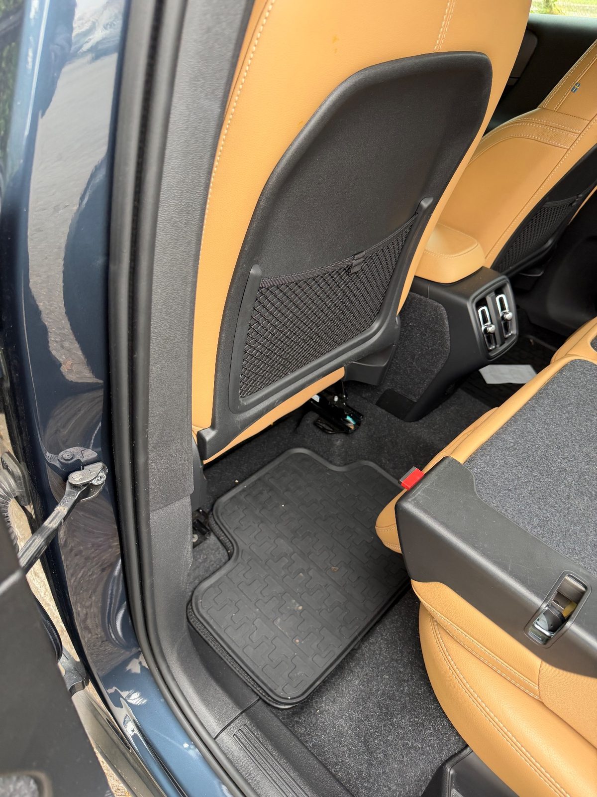 Rear footwell of a Volvo XC40 before detailing, with dust and debris on the mat