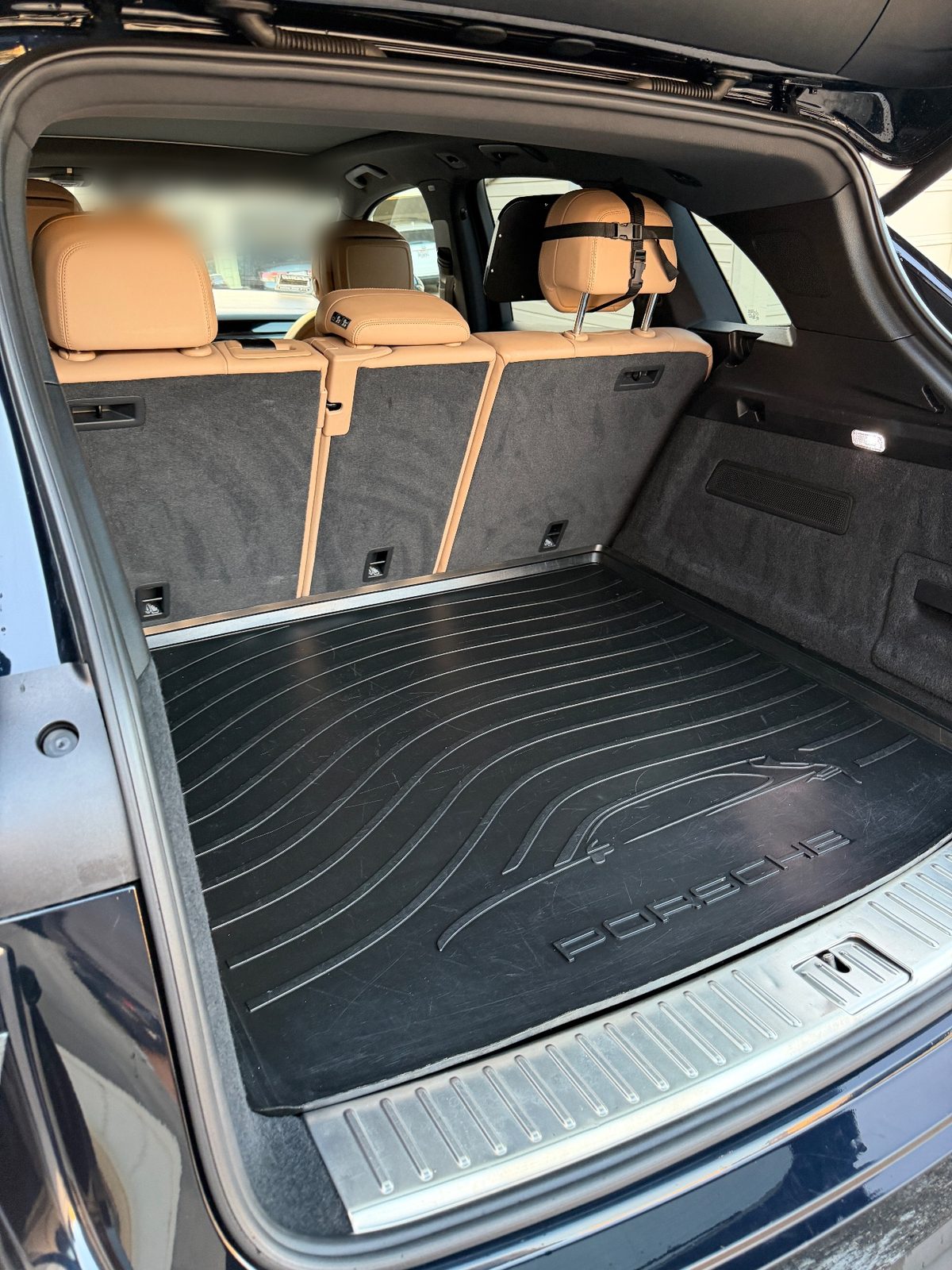 Clean cargo area of a Porsche Cayenne after detailing, rubber mat and sill free of dust