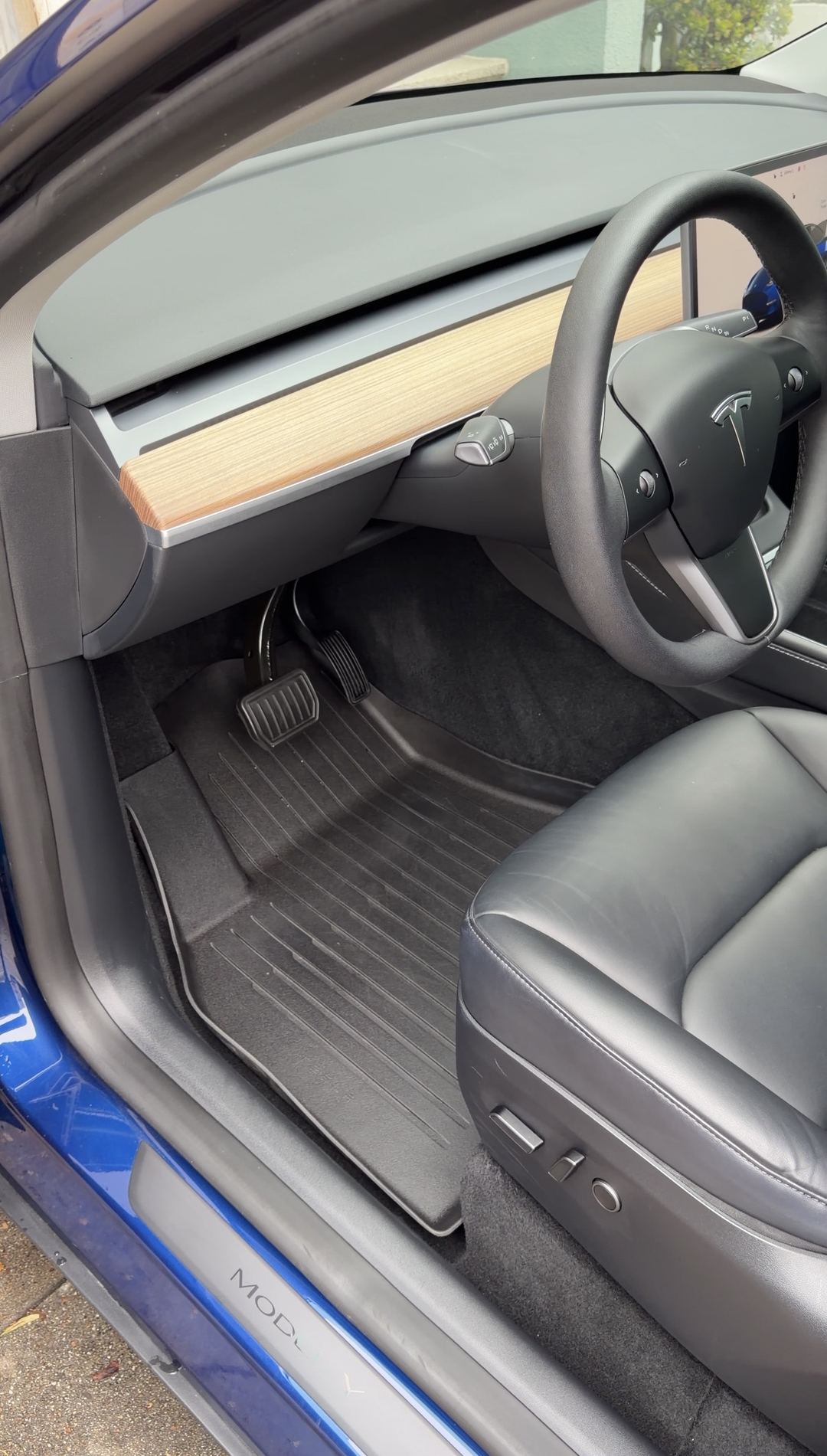Clean driver's footwell and cockpit of a Tesla Model Y after detailing, rubber floor liner spotless.