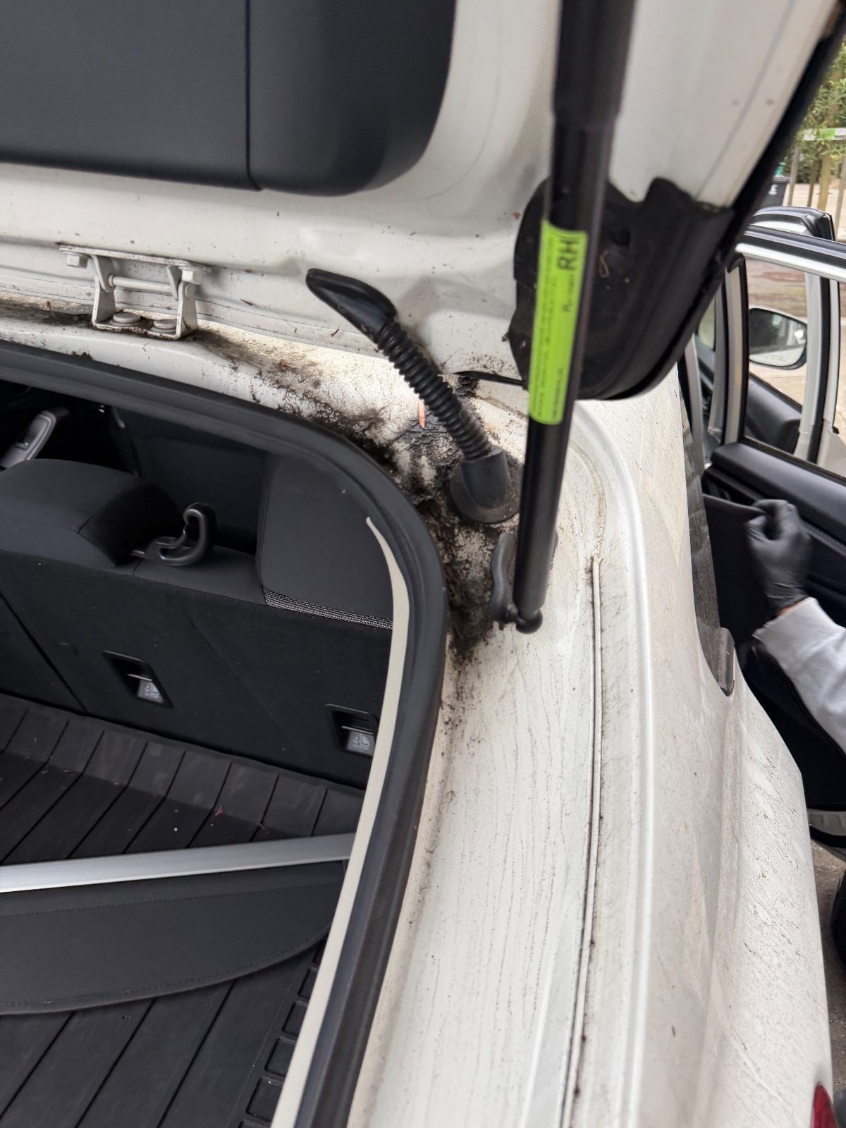 Right hatch strut and hinge gutter of a white Subaru Crosstrek in the Inner Richmond, San Francisco, before detailing