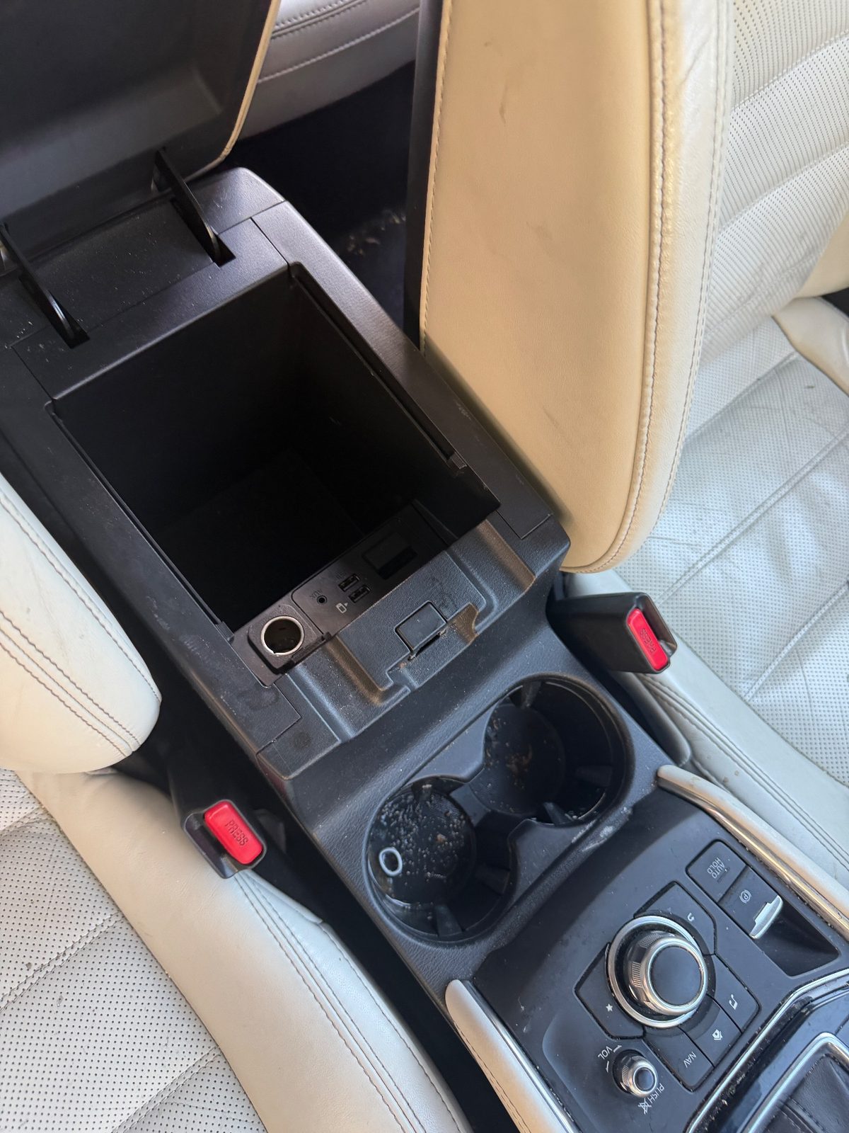 Open centre armrest and cupholders of a Mazda CX-5 before detailing, debris and residue in the cupholders