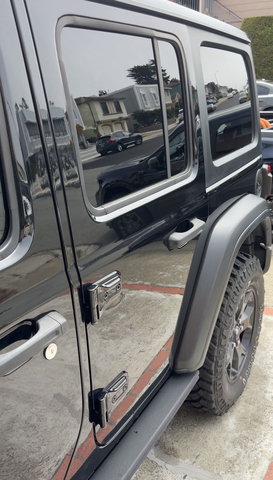Black Jeep Wrangler side doors and rear flare reflecting the street after cleaning