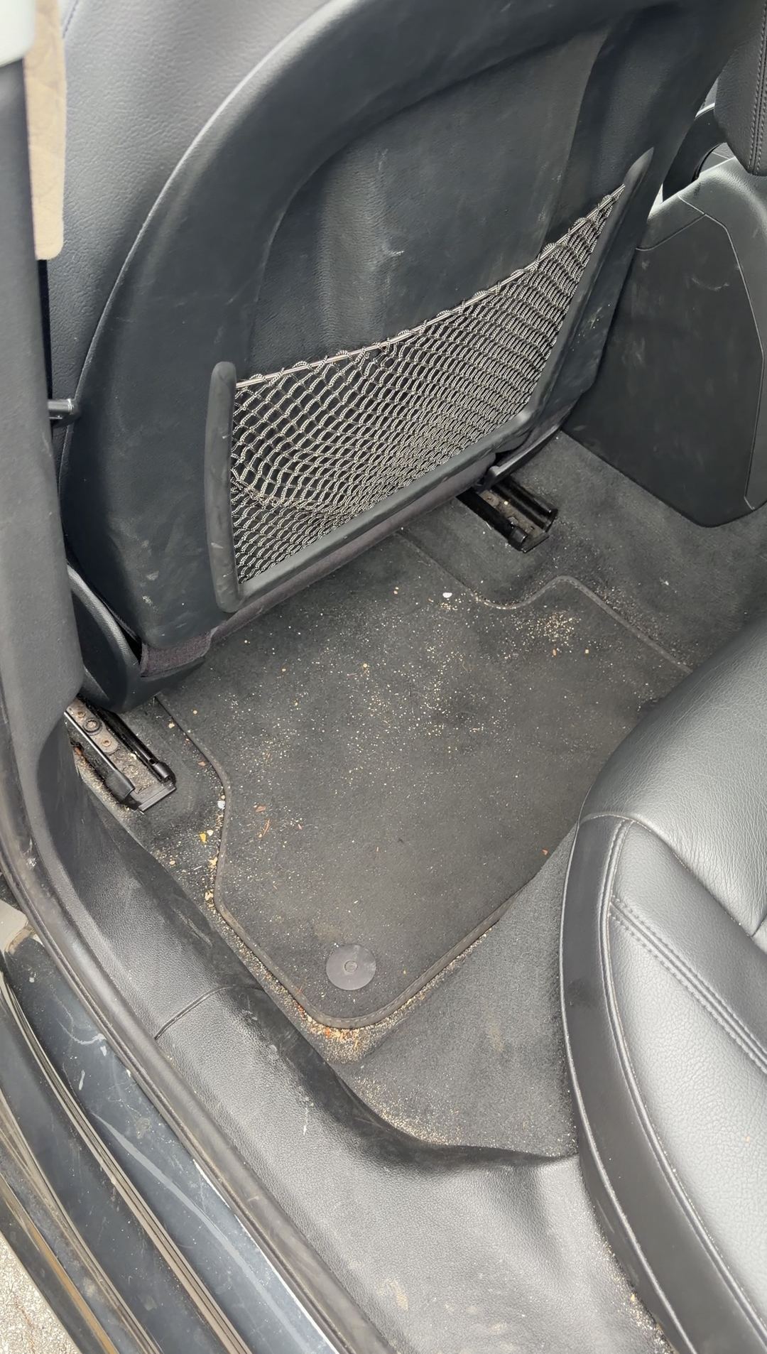 Grit and debris on the rear floor mat behind the driver seat of an Audi A4