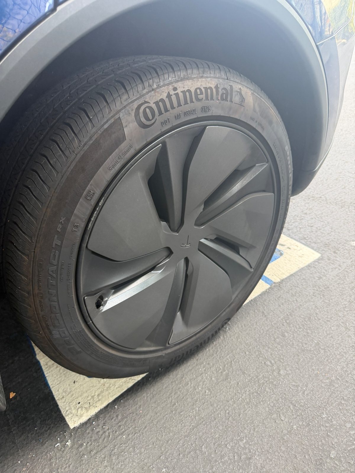 Dull tyre and dusty wheel on a blue Tesla Model Y before detailing