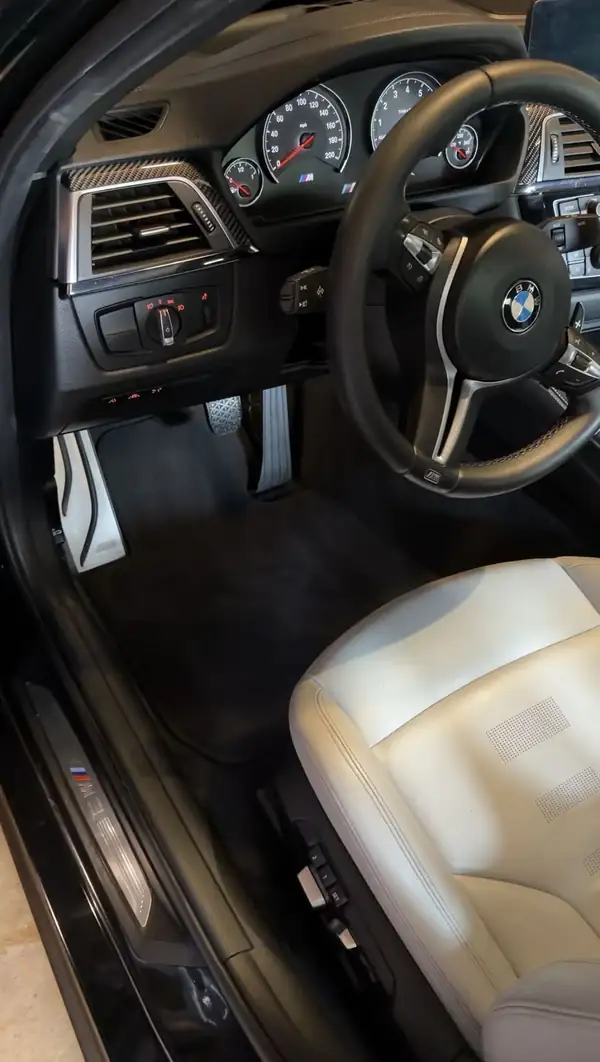 Cleaned driver's footwell of a BMW M3 with drilled aluminium pedals, M footrest and lit M3 door sill