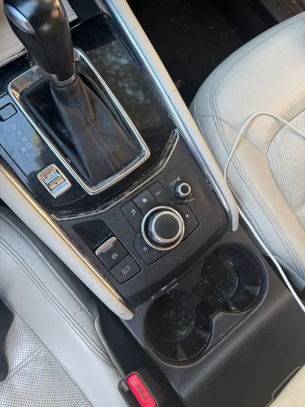 Centre console of a dark blue Mazda CX-5 before detailing, debris in the cupholders and grit around the shifter