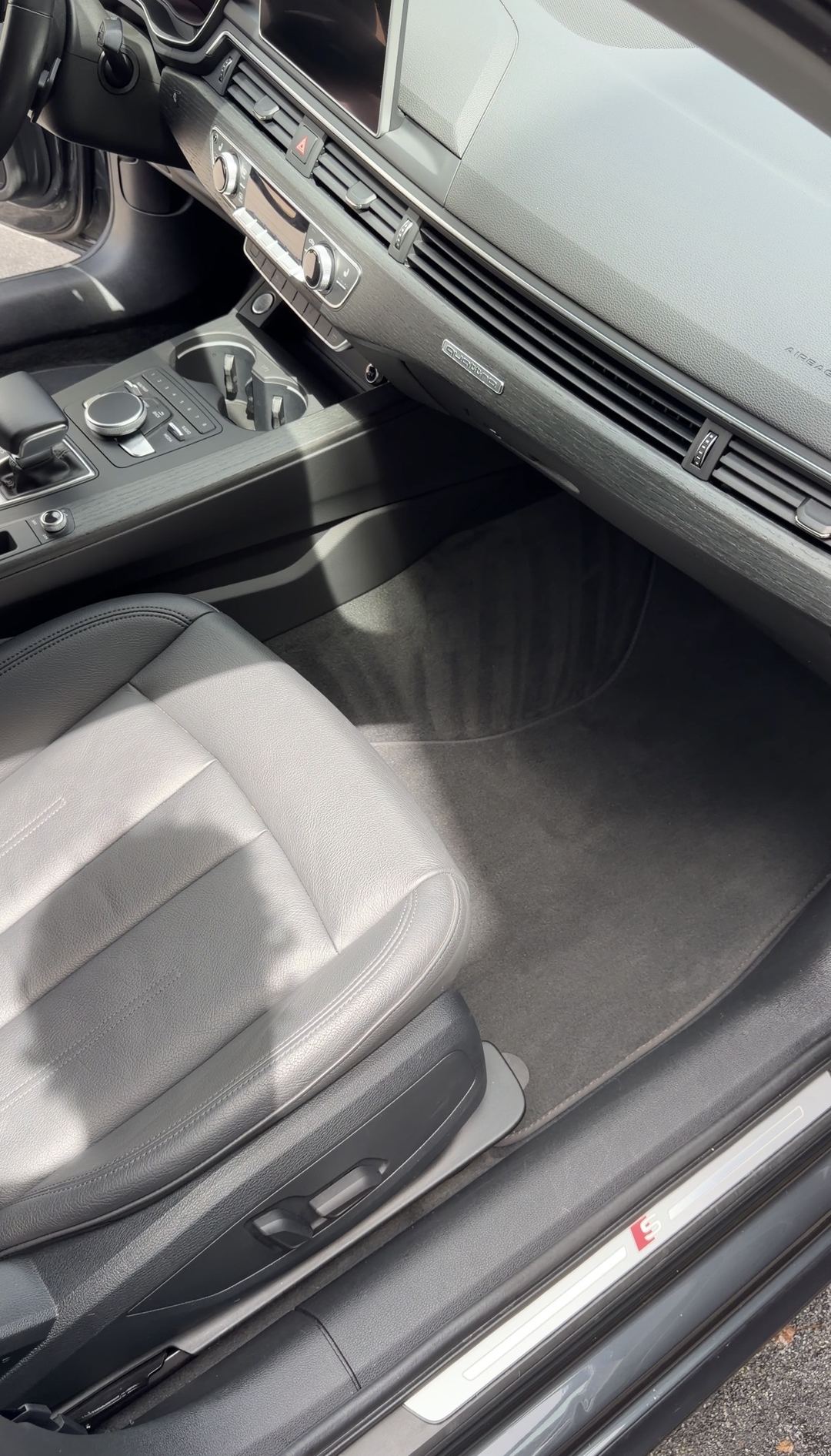 Vacuumed front passenger floor mat and clean sill of a grey Audi A4 with black leather seats
