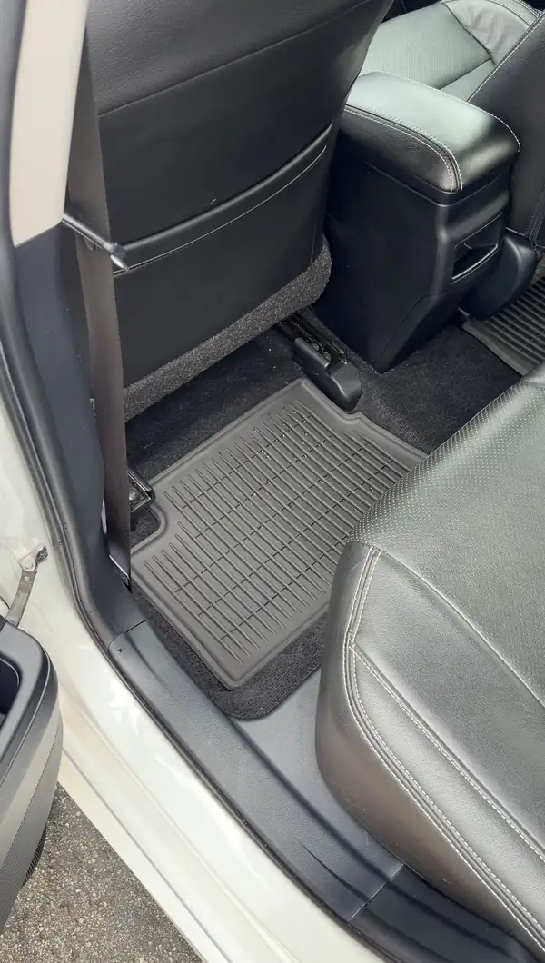 Rear driver-side footwell of a white Toyota Corolla iM after detailing, with a clean rubber floor liner sitting flat on freshly vacuumed carpet.