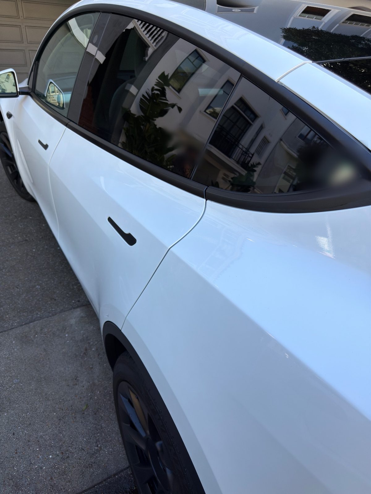 Glossy white rear door and quarter of a Tesla Model Y after detailing