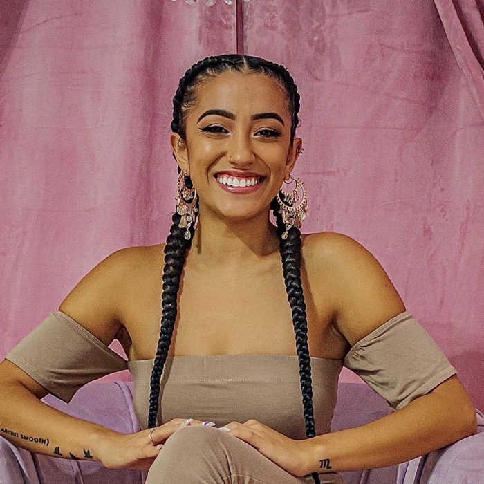 Ryin smiling in a pink velvet armchair