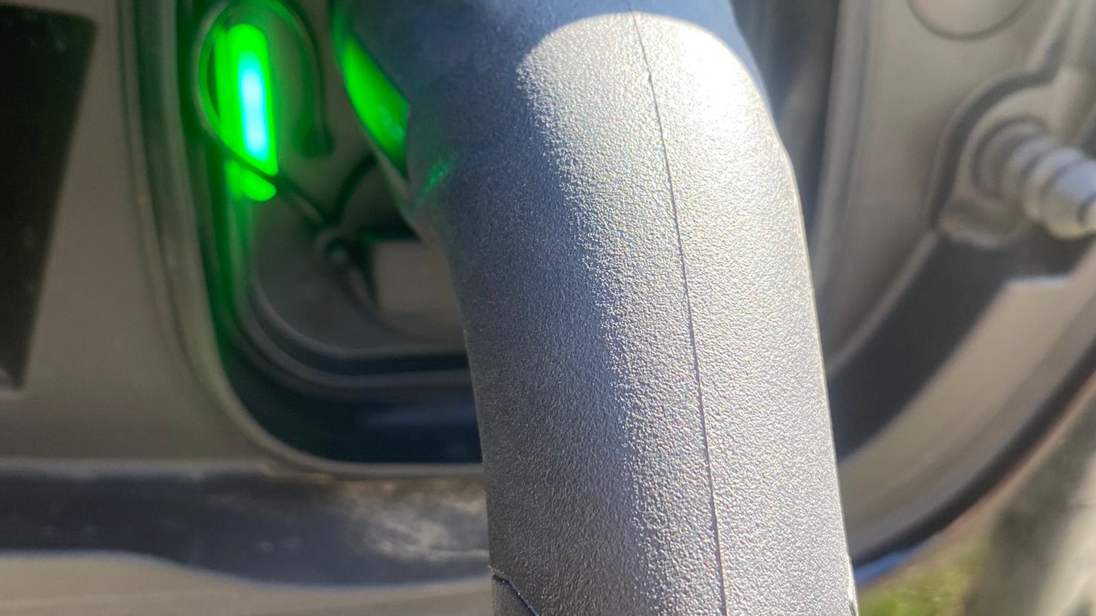 EV charging cable plugged into car with green charging indicator light EV charging cable plugged into car with green charging indicator light
