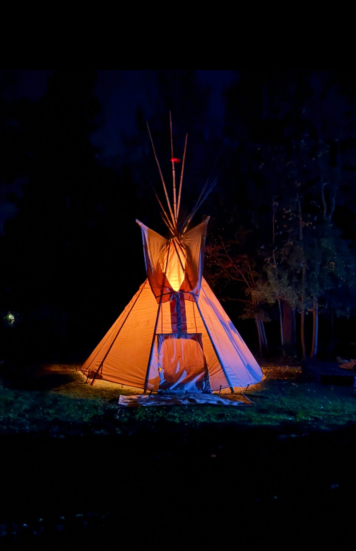 A tipi glowing from within at night