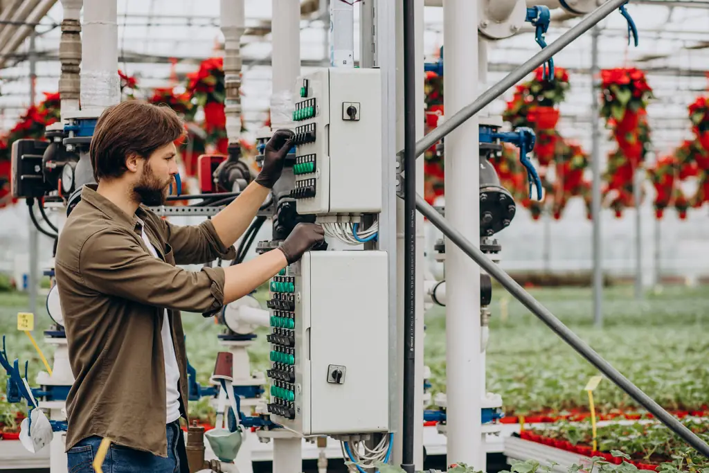 Electrician adjusting switches on a control panel in a commercial greenhouse