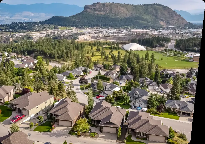 Aerial view of a residential neighbourhood with a mountain in the background in the Okanagan