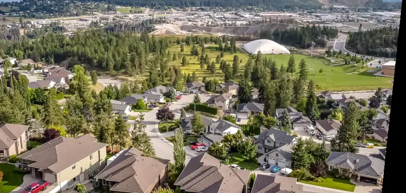 Aerial view of a residential neighbourhood with a mountain in the background in the Okanagan