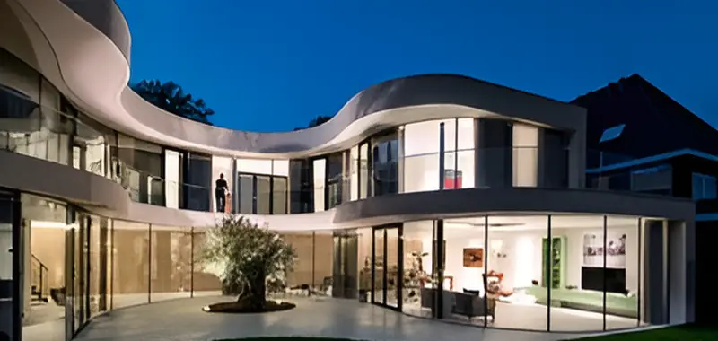 Modern home at dusk with warm interior and exterior lighting