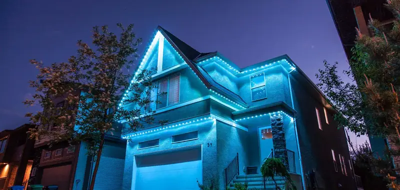 Two storey house at night with blue permanent LED trim lighting along the roofline
