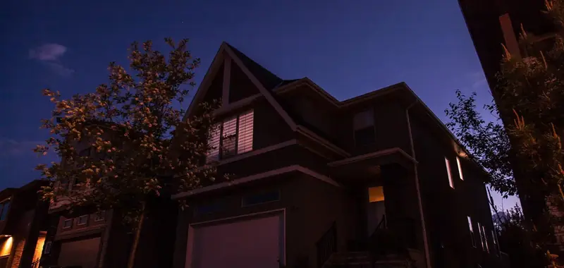 Two storey home at dusk with warm light glowing from the windows