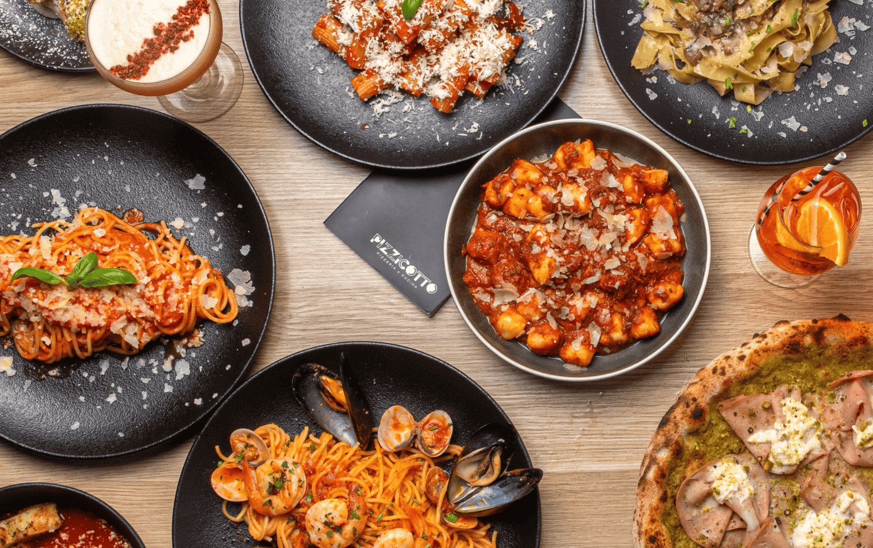Signature overhead flatlay of Pizzicotto wood-fired pizza, fresh pasta and branded menu