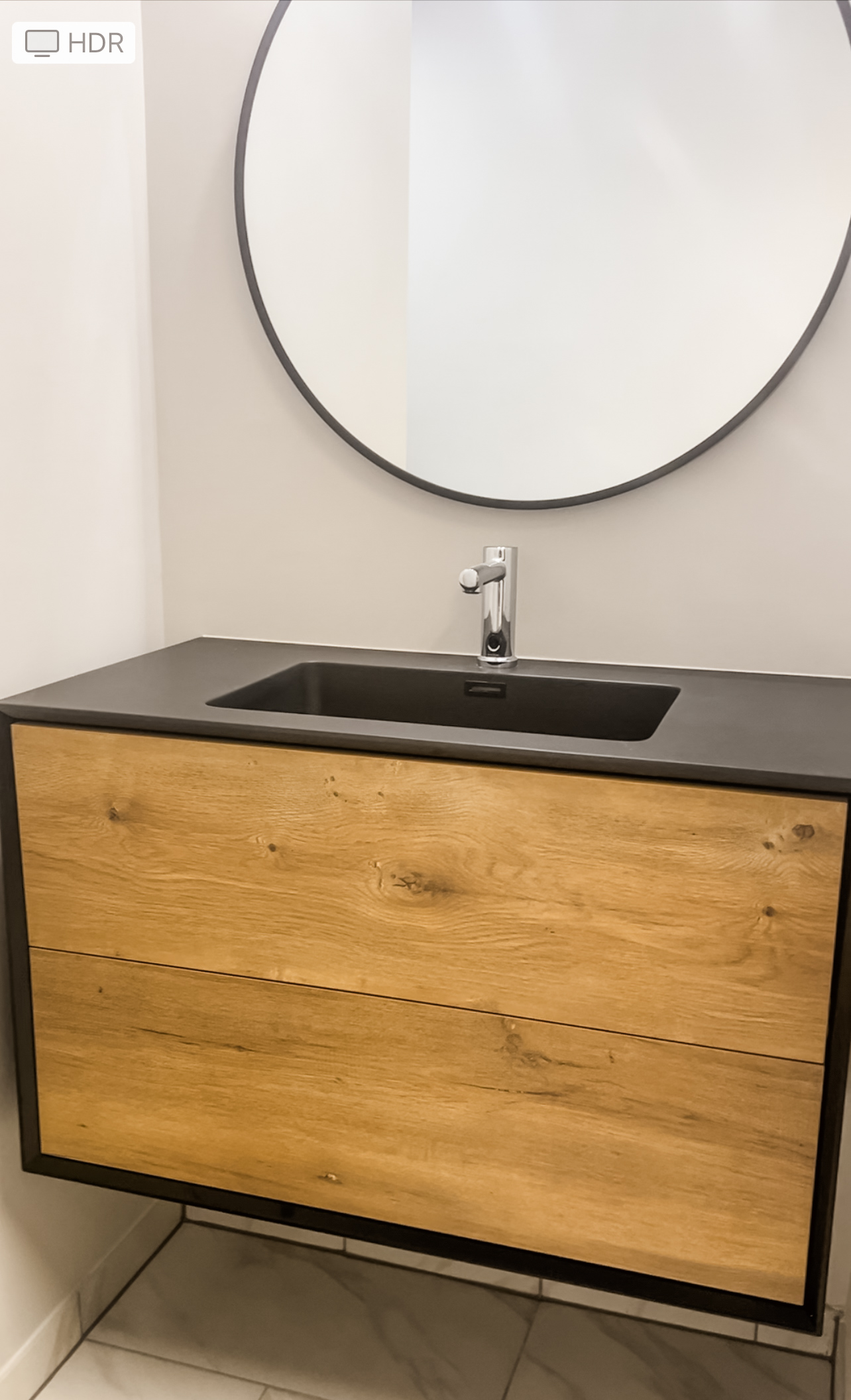Contemporary floating vanity with black sink basin and round mirror in small bathroom remodel