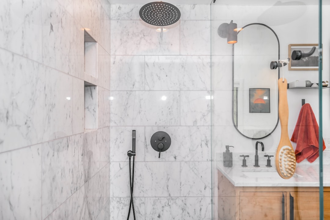 Modern walk-in marble tile shower with matte black fixtures and wood cabinets