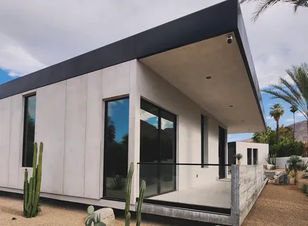 Exterior of a modern desert home with tinted floor-to-ceiling windows.
