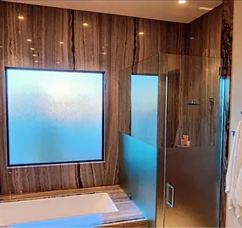 A bathroom window and shower enclosure finished with frosted privacy film, letting light through without a view in.