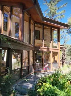 A wood-framed mountain home with window film applied across its large windows.
